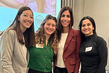 Group photo of female speakers standing in front of screen.