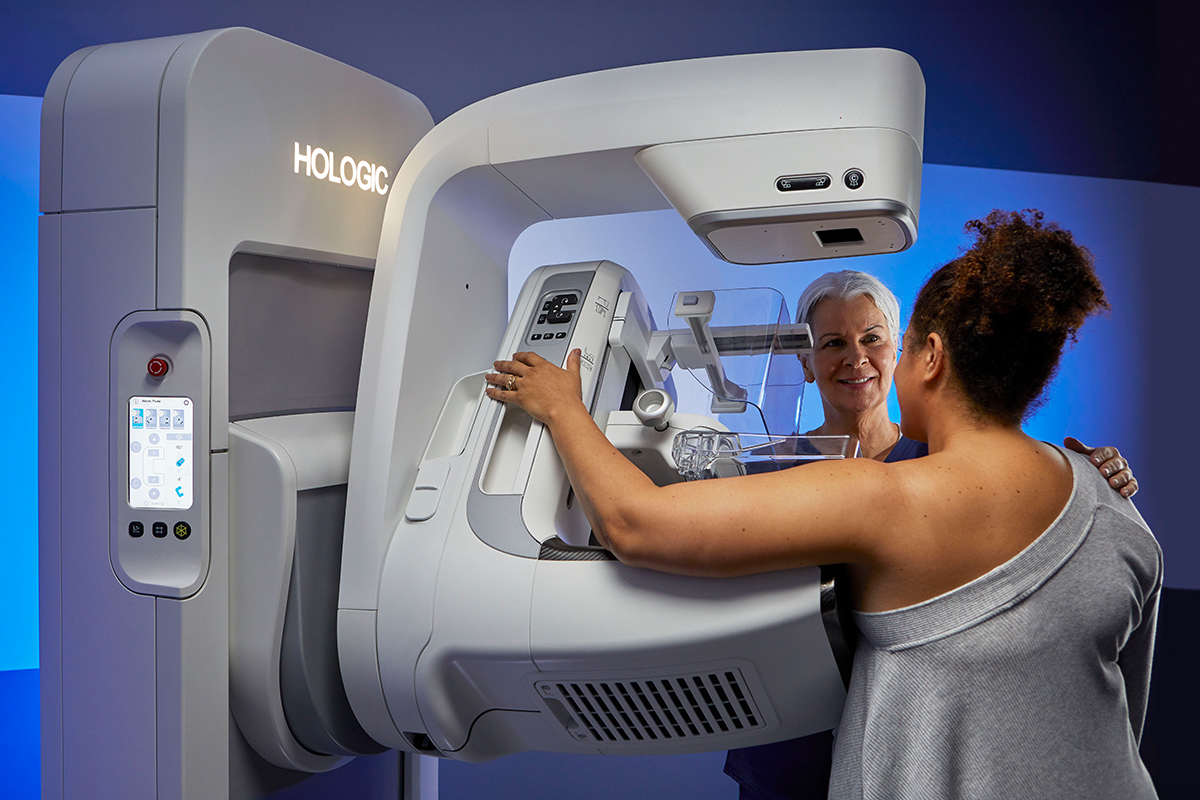 Woman sits in while chair while getting a mammogram.