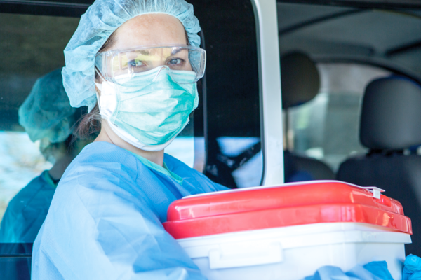 Person in mask holding organ transplant box