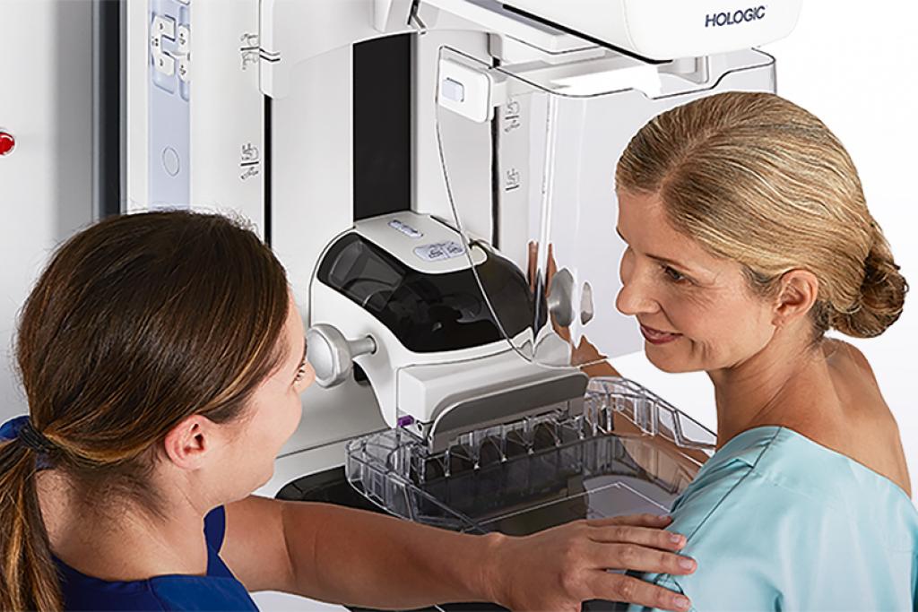 Technician speaking with patient at mammography station