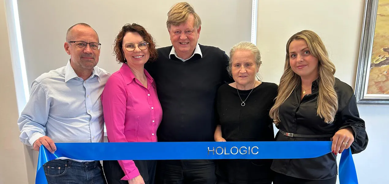 Group photo of people holding a banner with 2 cakes displayed