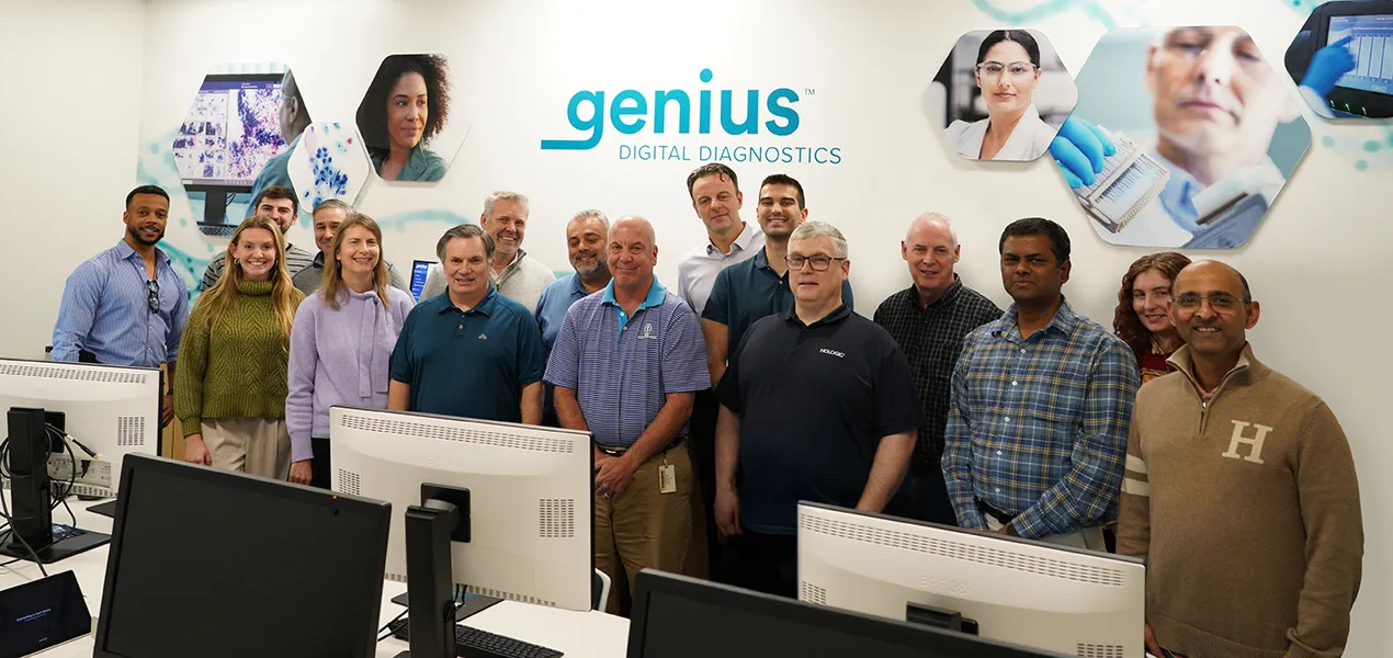 Group of people standing together in front of computer screens.