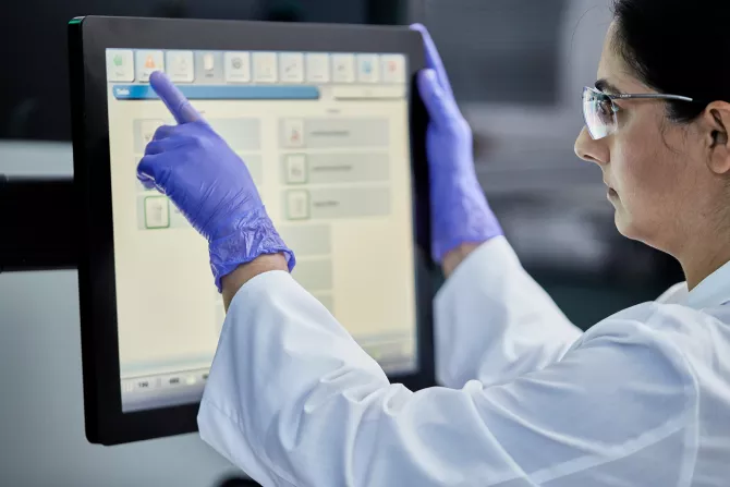 Technician interacting with display in lab setting.