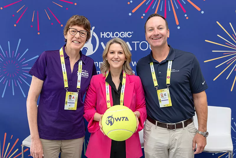 Group picture of representatives from Hologic and WTA holding large tennis ball.